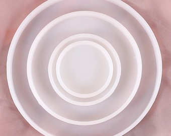 Può includere: Set di quattro stampi rotondi in silicone bianco per l'artigianato in resina. Gli stampi sono annidati l'uno nell'altro, con lo stampo più grande in basso e quello più piccolo in alto.