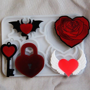 May include: Silicone mold with six different heart-shaped designs. The designs include a bat with a heart, a padlock with a keyhole, a key with a heart, a rose, a heart with wings, and a simple heart.
