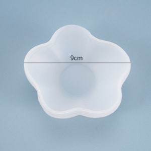 May include: White silicone mold shaped like a flower with five petals. The mold is 9 inches in diameter.