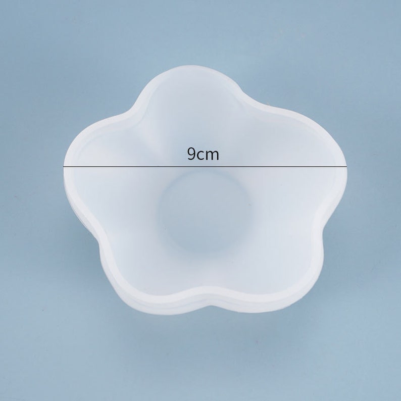 May include: White silicone mold shaped like a flower with five petals. The mold is 9 inches in diameter.