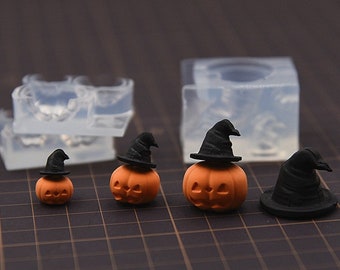 May include: Four miniature orange pumpkins with black witch hats. The pumpkins are different sizes and are arranged in a row on a black and white grid surface. There are three clear silicone molds in the background.
