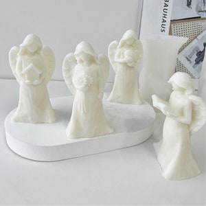 Può includere: Quattro statuine di angeli in ceramica bianca su una base ovale bianca. Gli angeli indossano tutti tuniche bianche e hanno le ali. Un angelo tiene una casetta per uccelli, un altro tiene un mazzo di fiori, un altro tiene un libro e un altro tiene un cuore.