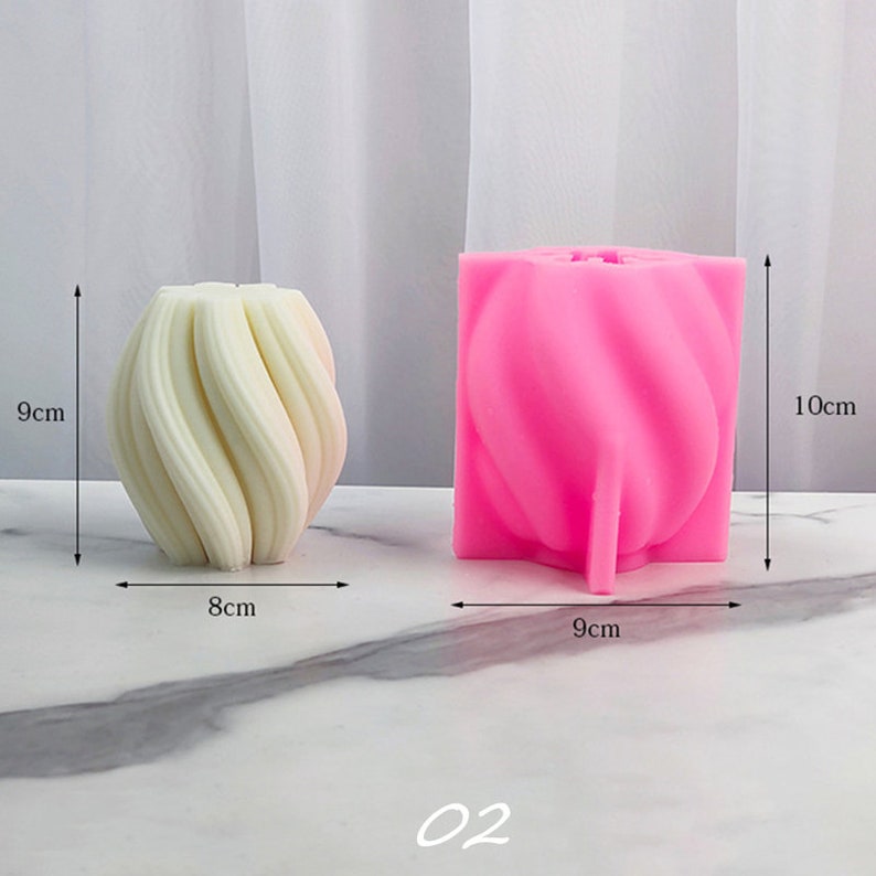 May include: Two silicone molds for making candles. The mold on the left is white and measures 8 cm wide and 9 cm tall. The mold on the right is pink and measures 9 cm wide and 10 cm tall. Both molds have a swirl design.