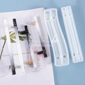 Könnte beinhalten: Eine Auswahl an Türgriffen aus Harz in Schwarz, Weiß und transparent. Einige Griffe haben Goldblatt-Akzente. Zwei transparente Silikonformen sind ebenfalls sichtbar. Der Text "BOBORESINART" ist auf dem Papier gedruckt.