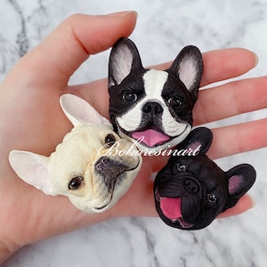 May include: Three resin figurines of French Bulldogs, each with a different color fur. One is black and white, one is white, and one is black. All three have their tongues sticking out.