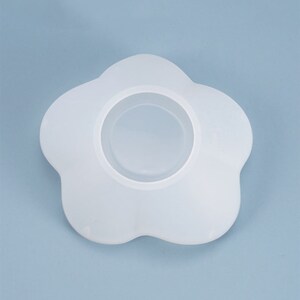 May include: White silicone mold shaped like a flower with a circular opening in the center.