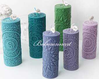 Può includere: Cinque candele decorative a pilastro con disegni intricati. Le candele sono in tonalità di verde e viola. I disegni includono mandala, foglie e simboli celesti.