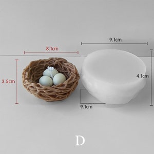 May include: A brown nest with three light green eggs, measuring 3.5 cm high and 8.1 cm wide. Next to it is a white, oval-shaped object, 4.1 cm high and 9.1 cm wide. The letter "D" is at the bottom.
