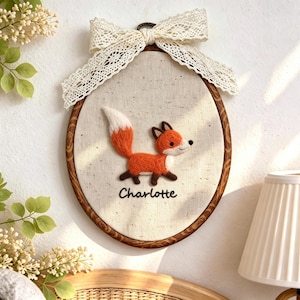 Peut inclure: D&eacute;coration murale brod&eacute;e ovale avec un renard orange et blanc et le nom "Charlotte". Le renard est plac&eacute; sur un tissu neutre, encadr&eacute; par un cerceau en bois et un n&oelig;ud en dentelle. Id&eacute;al pour une chambre d'enfant.