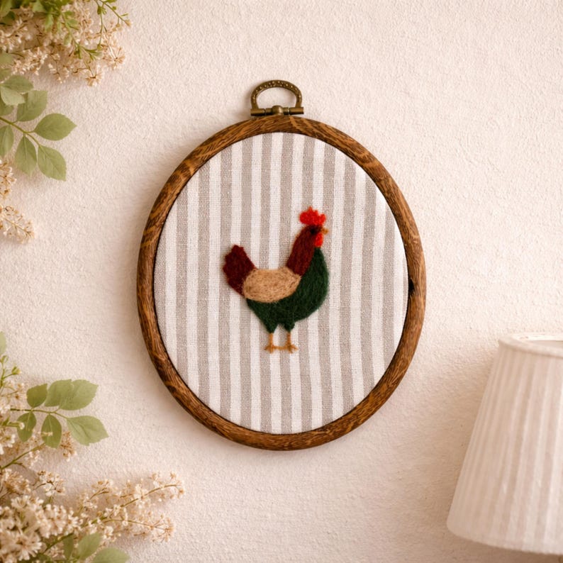 Peut inclure: Broderie d'un coq aux couleurs vives, rouge, marron et vert, encadr&eacute;e dans un cercle en bois. Le coq est plac&eacute; sur un fond &agrave; rayures grises et blanches. Le cadre en bois est de couleur marron fonc&eacute;.