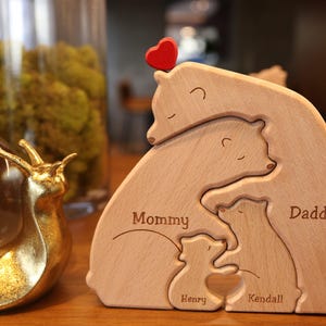May include: Wooden bear family puzzle with a red heart on top. The bears are labeled "Mommy", "Daddy", "Henry", and "Kendall".