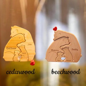 May include: Two wooden bear family puzzles with personalized names. The left puzzle is made of cedarwood and the right puzzle is made of beechwood. Both puzzles feature a heart at the center.