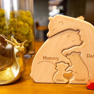 May include: Wooden bear family puzzle with the names Mommy, Daddy, Kendall, and Henry. The puzzle is made of light brown wood and has a natural finish.