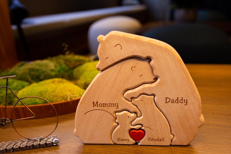 May include: Wooden bear family puzzle with the words "Mommy", "Daddy", "Henry", and "Kendall" engraved on the pieces. The bears are arranged in a hugging pose with a red heart in the center.