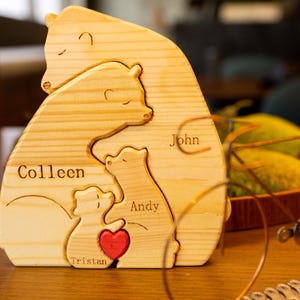 May include: Wooden bear family puzzle with the names Colleen, John, Andy, and Tristan. The bears are stacked on top of each other, with the largest bear at the bottom and the smallest bear at the top. The puzzle is made of natural wood and has a rustic look.