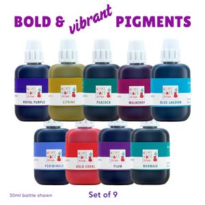 May include: A set of nine 30ml bottles of liquid pigment with white caps. The labels feature the text HOME WARE DESIGN CO and colour names: Royal Purple, Citrine, Peacock, Mulberry, Blue Lagoon, Periwinkle, Bold Coral, Plum, and Mermaid.