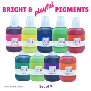 Może przedstawiać: Zestaw dziewięciu butelek z pigmentami w żywych kolorach, takich jak Vivid Pink, Blazing Blue i Rebel Red. Każda butelka ma białą zakrętkę i jest oznaczona nazwą koloru. Tekst brzmi "Bright & playful pigments" i "Set of 9". Każda butelka ma 30 ml.