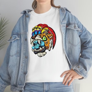May include: White t-shirt featuring a colorful graphic of a jaguar-like creature with a skull. The design includes orange, yellow, blue, and red accents. The shirt is made of a soft material.