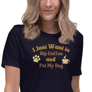 Könnte beinhalten: Ein marineblaues T-Shirt mit dem Text "I Just Want to Sip Coffee and Pet My Dog" in brauner und goldener Schrift. Ein Pfotenabdruck und ein Kaffeetassen-Symbol sind im Design enthalten.