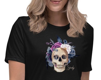 Könnte beinhalten: Schwarzes Damen-T-Shirt mit einem floralen Totenkopf-Design. Der Totenkopf ist von lila, weißen und blauen Blumen umgeben. Der Text "Spooky" ist unter dem Totenkopf gedruckt.