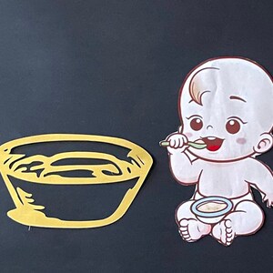 May include: A yellow bowl with a white interior and a cartoon baby holding a spoon and eating from a blue bowl.