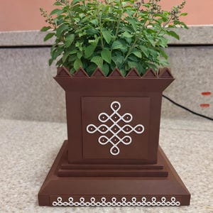 May include: A white ceramic mug with a black handle and the text "But First, Coffee" in a bold, black font. The mug is set against a blurred background, suggesting a cozy setting.