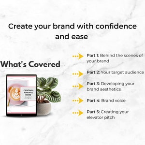 May include: A digital tablet displaying a pink and white ebook cover with the title "Creating a Powerful Brand". The ebook cover features a latte with latte art. The tablet is on a white marble surface with a green plant in a gray pot.