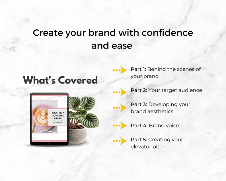 May include: A digital tablet displaying a pink and white ebook cover with the title "Creating a Powerful Brand". The ebook cover features a latte with latte art. The tablet is on a white marble surface with a green plant in a gray pot.