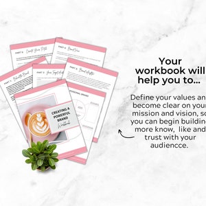 May include: A pink and white workbook with the title "Creating a Powerful Brand Workbook". The workbook is open to a page with a diagram titled "Personal Brand". A cup of coffee with latte art sits on a pink surface.