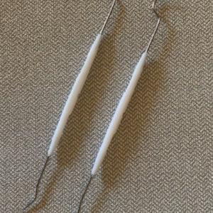 May include: Two dental tools with white handles and metal hooks at the ends.