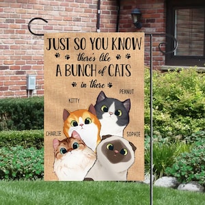 May include: A burlap garden flag with the text "Just so you know there's like a bunch of cats in there" and paw prints. The flag features five cartoon cats with the names Kitty, Peanut, Charlie, Sophie, and a fourth cat without a name.