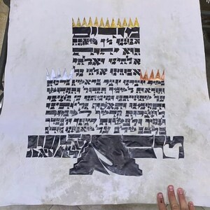 May include: A white parchment scroll with black Hebrew text and gold and silver crowns. The text is written in a decorative, stylized font.