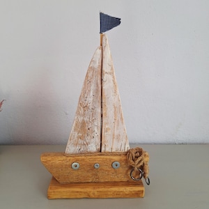 Rustieke zeilboot van drijfhout met blauwe vlag