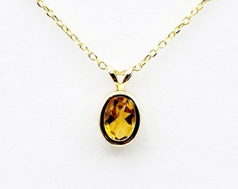 Op de afbeelding: Een gouden ketting met een hanger met een heldere ovale topaas-edelsteen.