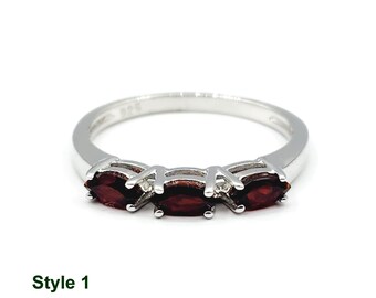 May include: A silver ring with three marquise-shaped red gemstones set in a row. The ring is simple and elegant.