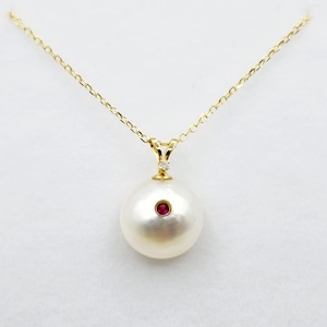May include: A gold chain necklace with a large white pearl pendant. The pearl has a small red gemstone set in the centre.