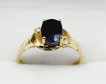 May include: A gold ring with a large oval-shaped blue sapphire gemstone and two smaller round diamonds on the band.