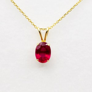Op de afbeelding: Een gouden ketting met een rode ovale robijn hanger.