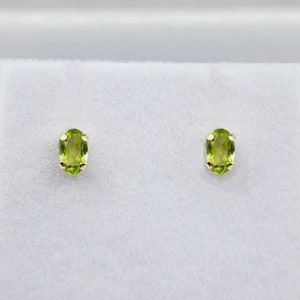 May include: A pair of gold earrings with oval-shaped green peridot gemstones.