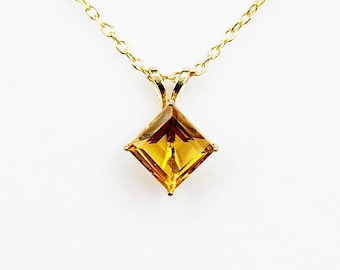 Op de afbeelding: Een gouden ketting met een vierkante, gefacetteerde, gele edelsteen hanger.