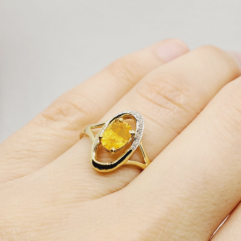 May include: A gold ring with a yellow oval gemstone surrounded by smaller clear gemstones.