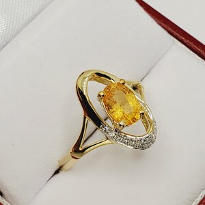 May include: A gold ring with a large oval-shaped yellow gemstone surrounded by a halo of smaller diamonds.