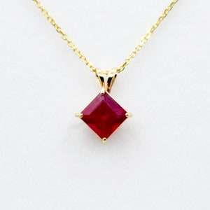 May include: A gold chain necklace with a square-shaped red ruby pendant.