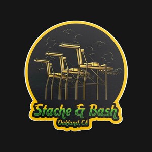May include: A yellow and green sticker with a black background. The sticker features a stylized illustration of a crane with the text "Stache & Bash Oakland, CA".