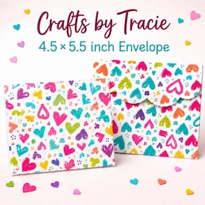 May include: Two white envelopes featuring a colorful pattern of hand-drawn hearts in pink, blue, yellow, orange, and purple. The text reads Crafts by Tracie and 4.5 x 5.5 inch Envelope. One envelope has a scalloped flap, and small heart confetti surrounds them.
