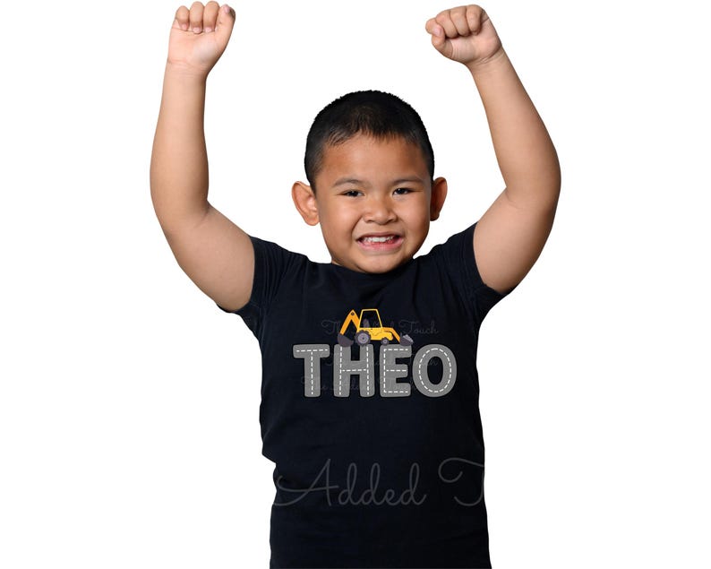 May include: A black t-shirt featuring a yellow construction vehicle graphic and the name "THEO" in grey outlined letters.
