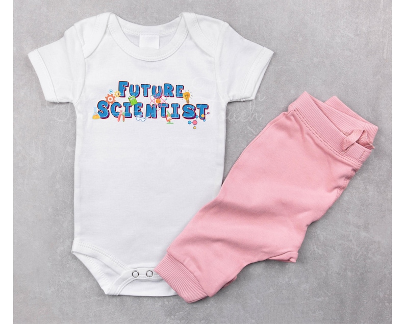 Pu&ograve; includere: Un body bianco per neonato con il testo "FUTURE SCIENTIST" in lettere blu e grafiche colorate a tema scientifico. Il body &egrave; abbinato a pantaloni rosa.