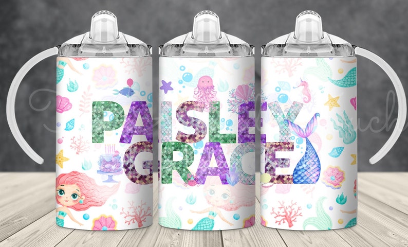 May include: Three white tumblers with clear lids and handles. Each tumbler features a different mermaid-themed design with a colorful, glittery name "Paisley Grace" on the middle tumbler.