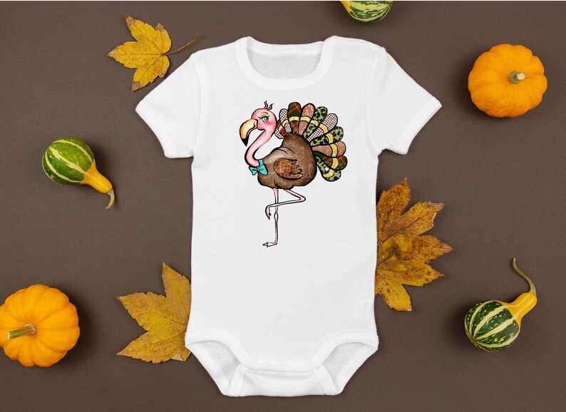 May include: White baby bodysuit featuring a whimsical illustration of a flamingo-turkey hybrid. The design includes a pink head, brown body, and colorful tail feathers. The bodysuit is surrounded by pumpkins and fall leaves.