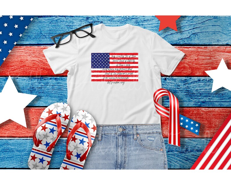 May include: White t-shirt with a red, white, and blue American flag graphic and text that reads "My Country, 'Tis of Thee, Sweet Land of Liberty, Of Thee I Sing."